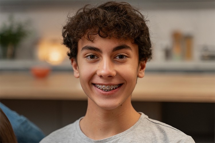 Teen wearing metal braces as part of Invisalign vs Traditional Braces treatment options.