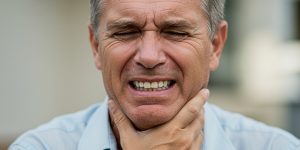 a man suffering from pain, wishing to cure TMJ permanently